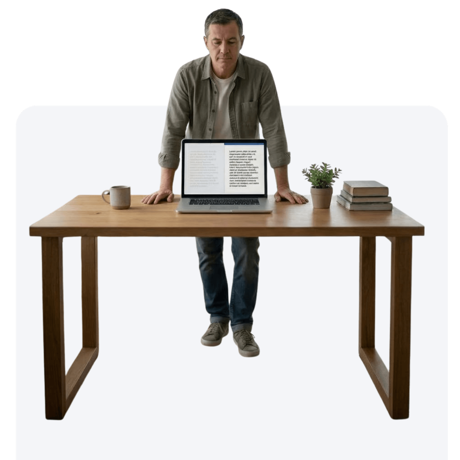 A man stands behind a wooden desk, leaning forward while reading text on a laptop screen, with a coffee mug, a small plant, and a stack of books placed on the desk.